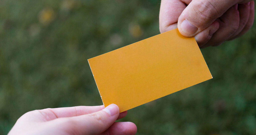 Close-up-of-handing-out-yellow-business-card