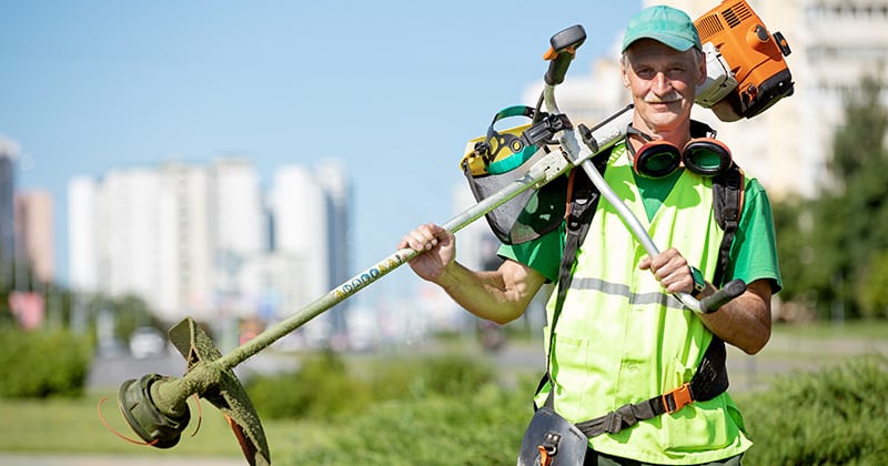Older male landscaper looking into the camera and holding an edger